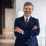 A smiling property manager in a suit standing in an office.